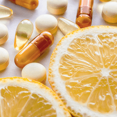 Une orange avec des compléments alimentaires sous forme de capsules, de comprimés et de gélules.